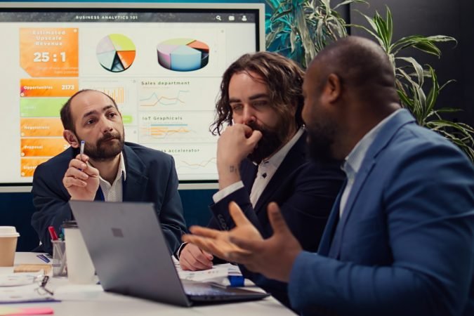 Corporate workers looking into project updates and timelines in boardroom, establishing budget and activities to achieve strategic objectives in a competitive business environment. Camera B.